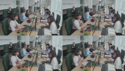 亚洲白领们在自己的办公工作站里忙碌地工作和交流，在开放式的规划中，心情愉快高清在线视频素材下载