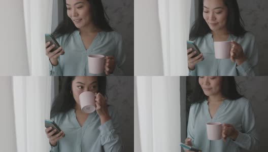 年轻女子走到窗前，一边喝着咖啡，一边用手机查看社交媒体高清在线视频素材下载