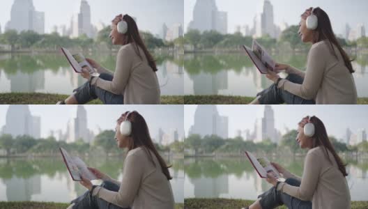 亚洲女人喜欢在早晨在城市公园听音乐和看书，人们在城市的自然环境中放松。高清在线视频素材下载