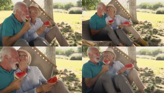 快乐的老夫妻在吊床上边吃西瓜边聊天。高清在线视频素材下载