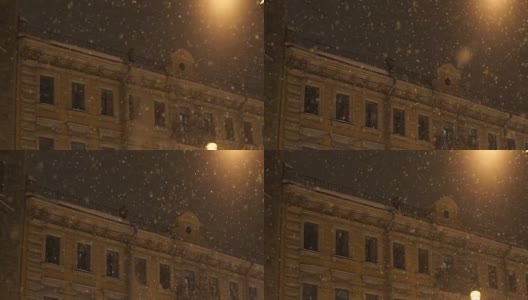 人从屋顶上扔下雪。晚上城里下大雪高清在线视频素材下载