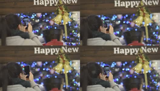 一个中国女孩在圣诞树下用手机拍照高清在线视频素材下载