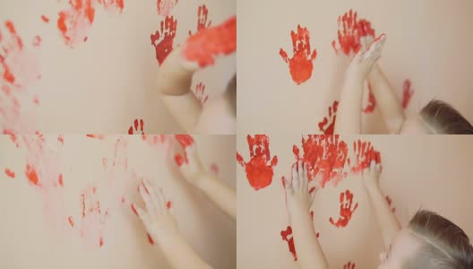 快乐可爱的小男孩在墙上留下他的红色手印玩得很开心。年轻的幸福的家庭。母亲和孩子的概念。Slowmotion高清在线视频素材下载