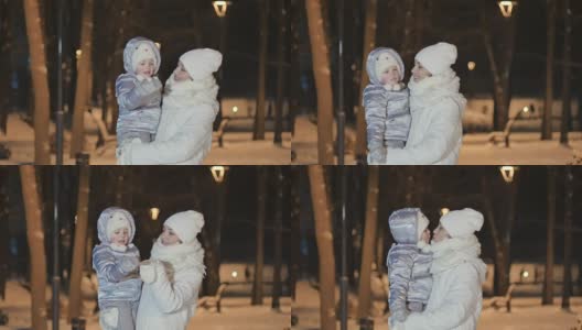 在冬天的公园里，年轻的妈妈牵着女儿的手和她亲吻高清在线视频素材下载