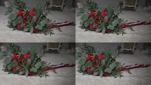 床上放着漂亮的婚礼花束，是用丝带裹着的红玫瑰和牡丹。特写镜头。高清在线视频素材下载