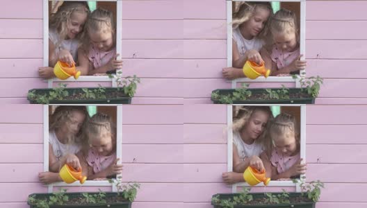 小女孩们一起在粉红色的玩具屋的窗台上浇花高清在线视频素材下载
