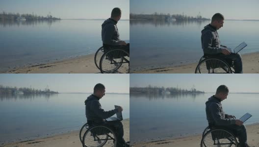 一个身体残疾的人坐在海边的轮椅上，手里拿着笔记本电脑高清在线视频素材下载