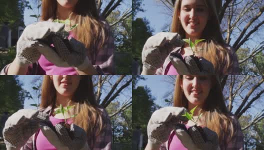 微笑的高加索少女在花园里工作，戴着手套，检查植物高清在线视频素材下载