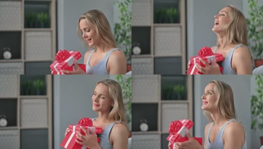 兴奋的金发女人微笑着打开红色的节日礼品盒与弓有积极的情绪高清在线视频素材下载