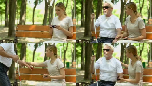 有爱心的女孩帮助有视力障碍的男人坐在她旁边的长椅上高清在线视频素材下载