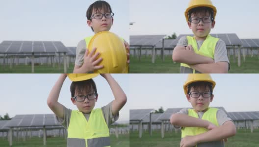戴眼镜的男孩穿防护服和头盔。他双臂交叉站在太阳能电池板前。用于使用太阳能的可再生能源相关应用高清在线视频素材下载