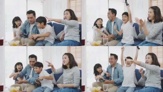 快乐亚洲家庭爸爸，妈妈和孩子有趣的玩电子游戏与技术控制台在家里的客厅。高清在线视频素材下载