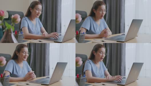 亚洲自由职业妇女戴着耳机在视频电话聊天在家里工作。高清在线视频素材下载