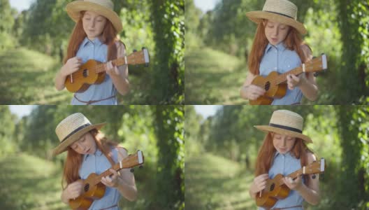 中镜头的肖像快乐熟练的高加索红发女孩唱歌玩尤克里里户外。阳光明媚的日子里，自信的青少年音乐家在春夏季的公园里享受业余爱好。人才和生活方式。高清在线视频素材下载