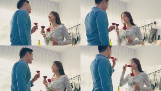 亚洲年轻情侣在情人节举杯畅饮。可爱浪漫的新婚男女在家里厨房共进晚餐庆祝结婚纪念日高清在线视频素材下载