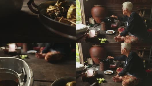 生活方式资深亚洲妇女坐在烹饪食物，慢动作高清在线视频素材下载