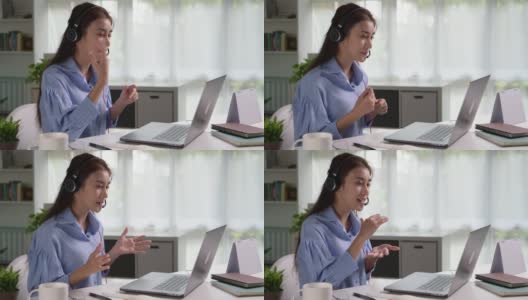 在工作中感到快乐和积极。年轻的亚洲女商人戴着耳机在笔记本电脑上与客户进行视频通话。年轻的亚洲女性提供在线教育课程讲座，咨询客户。高清在线视频素材下载