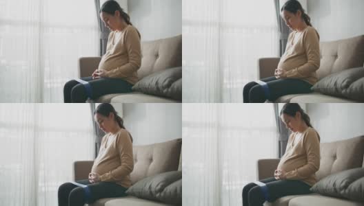 怀孕的妈妈在家里的客厅里练习弹性阻力带高清在线视频素材下载