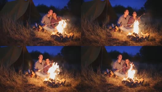 年轻夫妇在篝火上准备晚餐高清在线视频素材下载