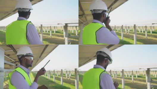 侧视图:非洲青年工程师，穿着防护服，戴着安全眼镜和安全帽，通过无线电与团队联系高清在线视频素材下载