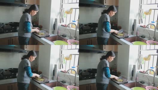 家庭烹饪:一位老年妇女在切蔬菜高清在线视频素材下载