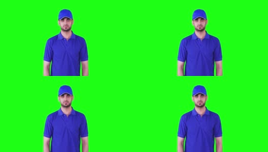 视频画面中，一名自信的送货员穿着蓝色制服，双手合十，站在工作室里，背景是绿色的屏幕高清在线视频素材下载