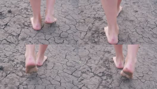 光着脚的女孩走在干涸的湖面上，干旱，土地裂缝，没有水。高清在线视频素材下载