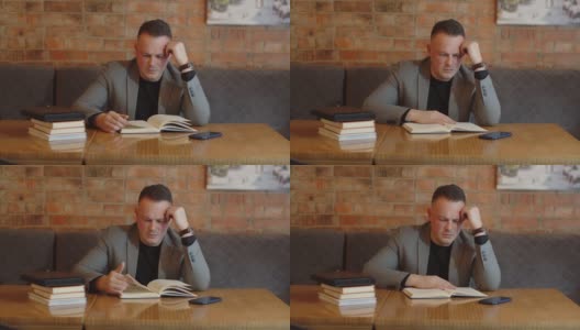 一个男人在咖啡馆的桌子上看书高清在线视频素材下载