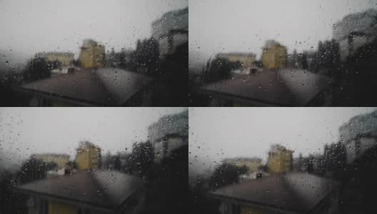 在恶劣的天气和下雨时，你可以看到窗外的城市。水滴从玻璃上滴下来高清在线视频素材下载