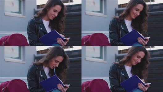 女学生坐在外面的现代木凳上写笔记本高清在线视频素材下载