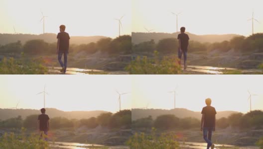 日落时分，印度古吉拉特邦的万卡纳，一名印度男子正走在河边，背景是山上的风车。日落时分，一名男子在河边风景优美地散步。高清在线视频素材下载
