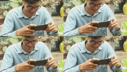 年轻的亚洲快乐男子坐在公园里用智能手机高清在线视频素材下载