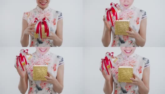 正面特写:中国/亚洲妇女打开她手中的一个金色的大礼盒，她从她的家人，亲戚和朋友的新年快乐，在中国的新年节日，穿着旗袍白色的衣服高清在线视频素材下载