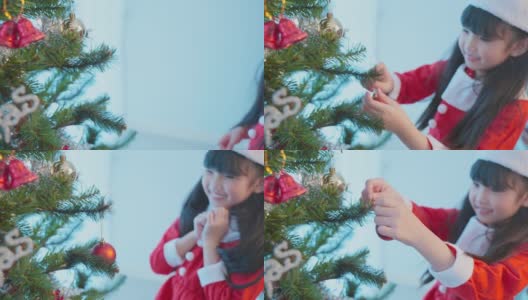 亚洲年轻快乐的女孩孩子戴着圣诞帽，装饰圣诞树。小可爱的孩子穿着红布感到兴奋庆祝节日圣诞节感恩节派对在客厅在房子。高清在线视频素材下载
