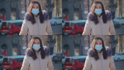 白天，一名留着黑色长发的女子站在城市街道上，戴着口罩抵御空气污染和冠状病毒高清在线视频素材下载