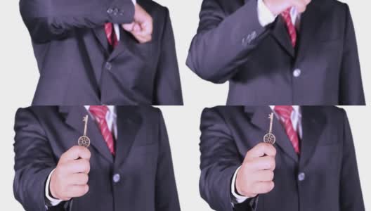 视频画面显示，一名男性企业家从西装口袋里拿着一把老式钥匙，背景是白色的高清在线视频素材下载