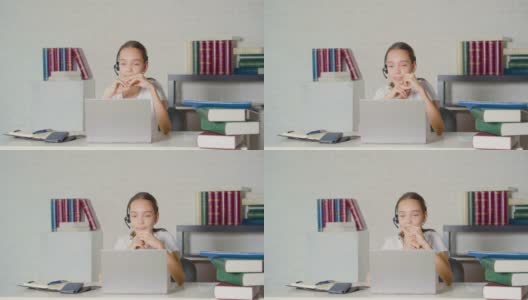 一个十几岁的女孩在一台笔记本电脑前上在线课程。她和老师交谈，并做手势高清在线视频素材下载