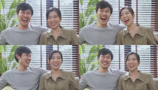 幸福的亚洲结婚情侣微笑着在家里的沙发上用温柔喜悦的表情牵手相拥，一起描绘亚洲男女青年甜蜜的关系高清在线视频素材下载