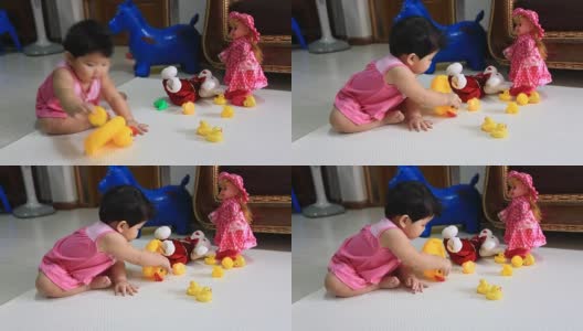 亚洲婴儿坐在地板上玩黄色的鸭子娃娃高清在线视频素材下载