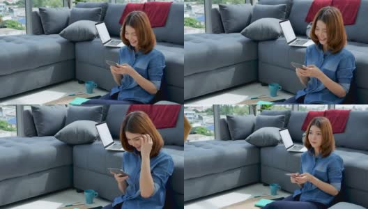 妇女在家工作的笔记本电脑在线会议在家庭办公室。亚洲女企业家用笔记本电脑坐在沙发上科技新常态的生活方式。快乐的女人打字键盘笔记本电脑高清在线视频素材下载