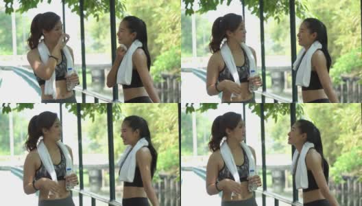 一组两个朋友美丽的亚洲健身女人在运动服和毛巾休息交谈后一起跑步锻炼。劳累的女性上午在公园户外训练后休息高清在线视频素材下载