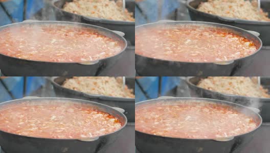 食物在铸铁锅里，志愿者在柴炉上准备饭菜，难民营，为乞丐准备热汤高清在线视频素材下载