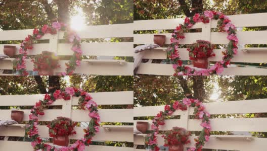 白色的篱笆上，挂着一个大的粉红色花和荚蒾花环高清在线视频素材下载