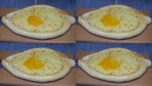 鸡蛋倒在khachapuri(格鲁吉亚奶酪糕点)上高清在线视频素材下载