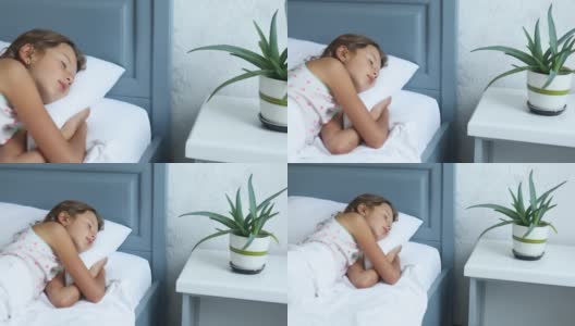 小女孩睡在一张又大又舒适的床上，白色的床单高清在线视频素材下载