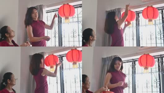 年轻的亚洲孙女帮助她的祖母准备挂新的红色的中国灯笼高清在线视频素材下载