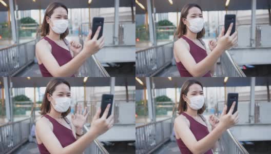 慢动作场景:年轻的亚裔员工女性，早上戴着口罩站在公共交通入口处，用智能手机上班，追求新常态和健康的生活方式理念高清在线视频素材下载