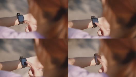 年轻的女运动员在公园跑步的后视图，同时使用智能手表检查她自己高清在线视频素材下载
