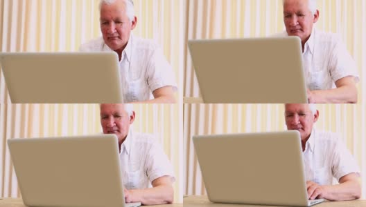 一个老人坐在桌子前用笔记本电脑高清在线视频素材下载
