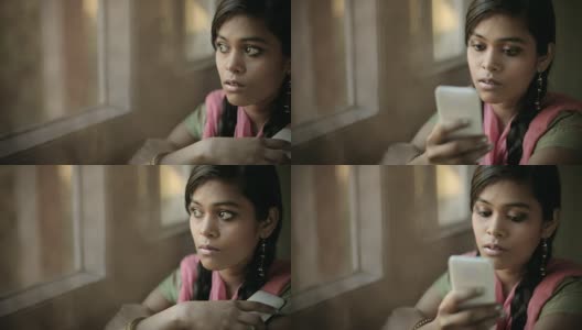 美丽安详的印度女孩坐在窗边读短信。高清在线视频素材下载